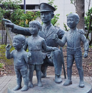 神奈川県警の正門に向かって右側、歩道沿いに建っている「警察官と子供像」。警察官が指さす先には一体何があるのだろうか…？（答えは本文で）