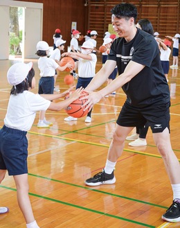 俊野選手（右）らとバスケの練習をする児童たち