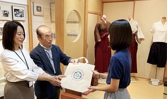 明治時代の袴など歴代の制服が展示される前で、来場者５万人達成の記念セレモニーが行われた