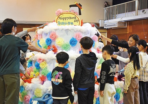 誕生日ケーキに点火する児童ら