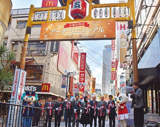 新しくなったアーチの下でテープカット