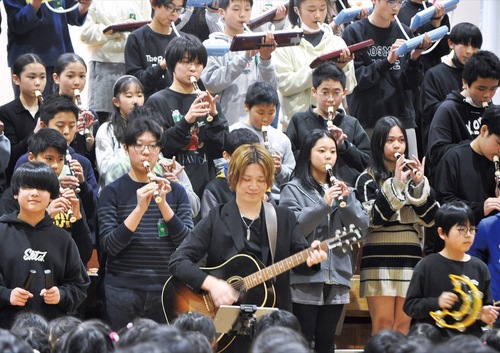 卒業生で作編曲家・ギタリストの奈良さんが同校の校歌をアレンジし、６年生たちと一緒にお祝いの合奏をした