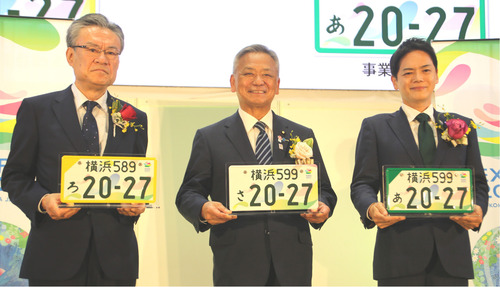 ５月３日の発表会で特別仕様のナンバープレートを手にする（左から）河村事務総長、高橋副大臣、山中市長