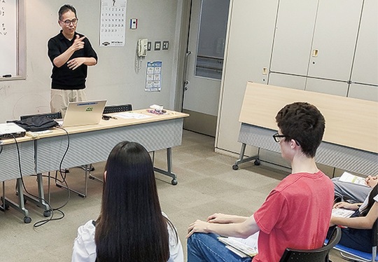 手話講座であいさつする市聴覚障害者協会の小島理事長（左奥）