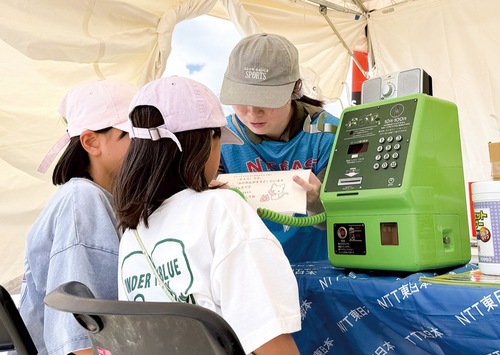 公衆電話で体験する参加者＝同社提供