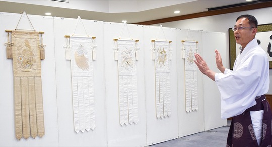 復元された白い四神旗＝右＝と古くから伝わる旧四神旗＝左＝について説明する阿久津宮司