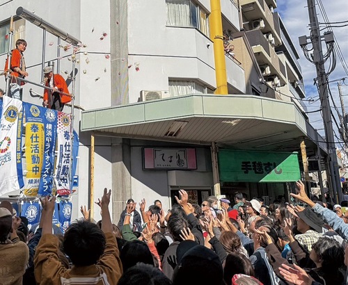 集まった多くの人が手を伸ばして餅を受け取った（提供）