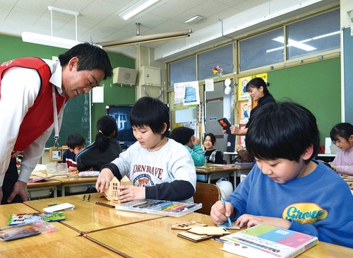 木に色を塗り組み立てる児童