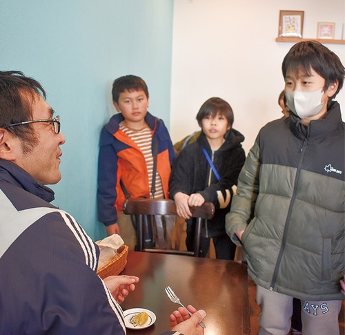 サツマもちを食べる客に感想を聞く児童
