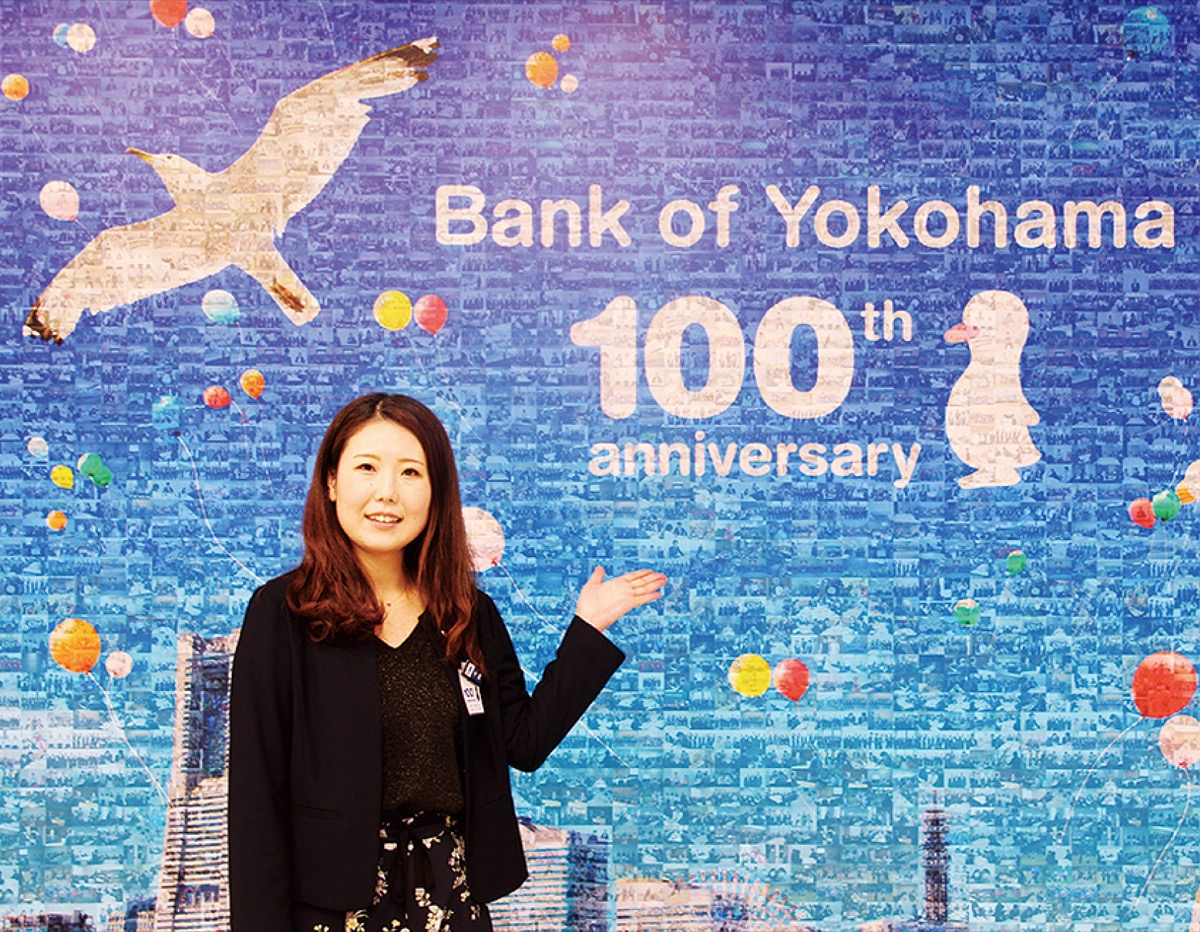 ７００枚以上の行員の写真を使用したモザイクアートを紹介する中島さん