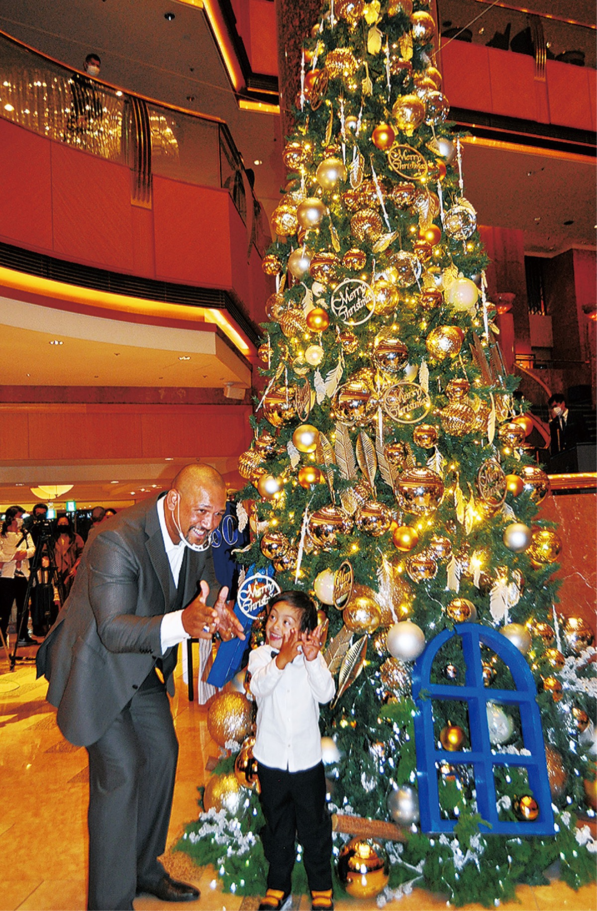 ホテルロビーのツリーの前で長男と一緒にポーズを決めるラミレスさん