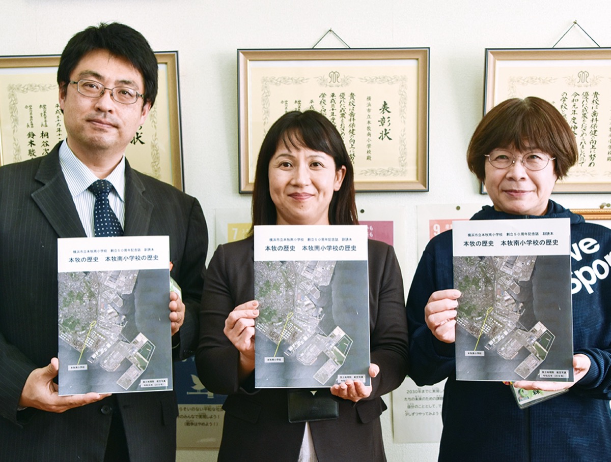 完成した歴史本を手にする谷口校長（中央）と森教諭（右）、針持拓郎副校長