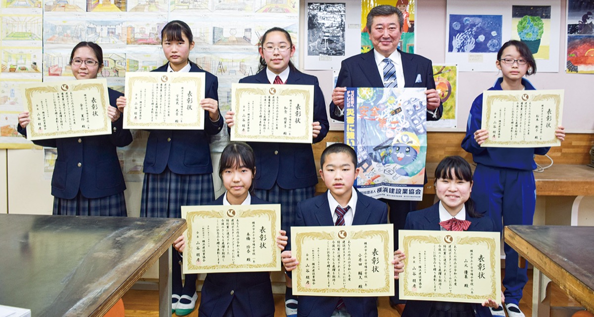 ポスターを手にする山谷会長と十日市場中の受賞者