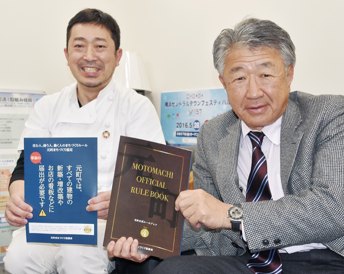 改訂版を手にする原会長(右)と街づくり委員長の打木さん