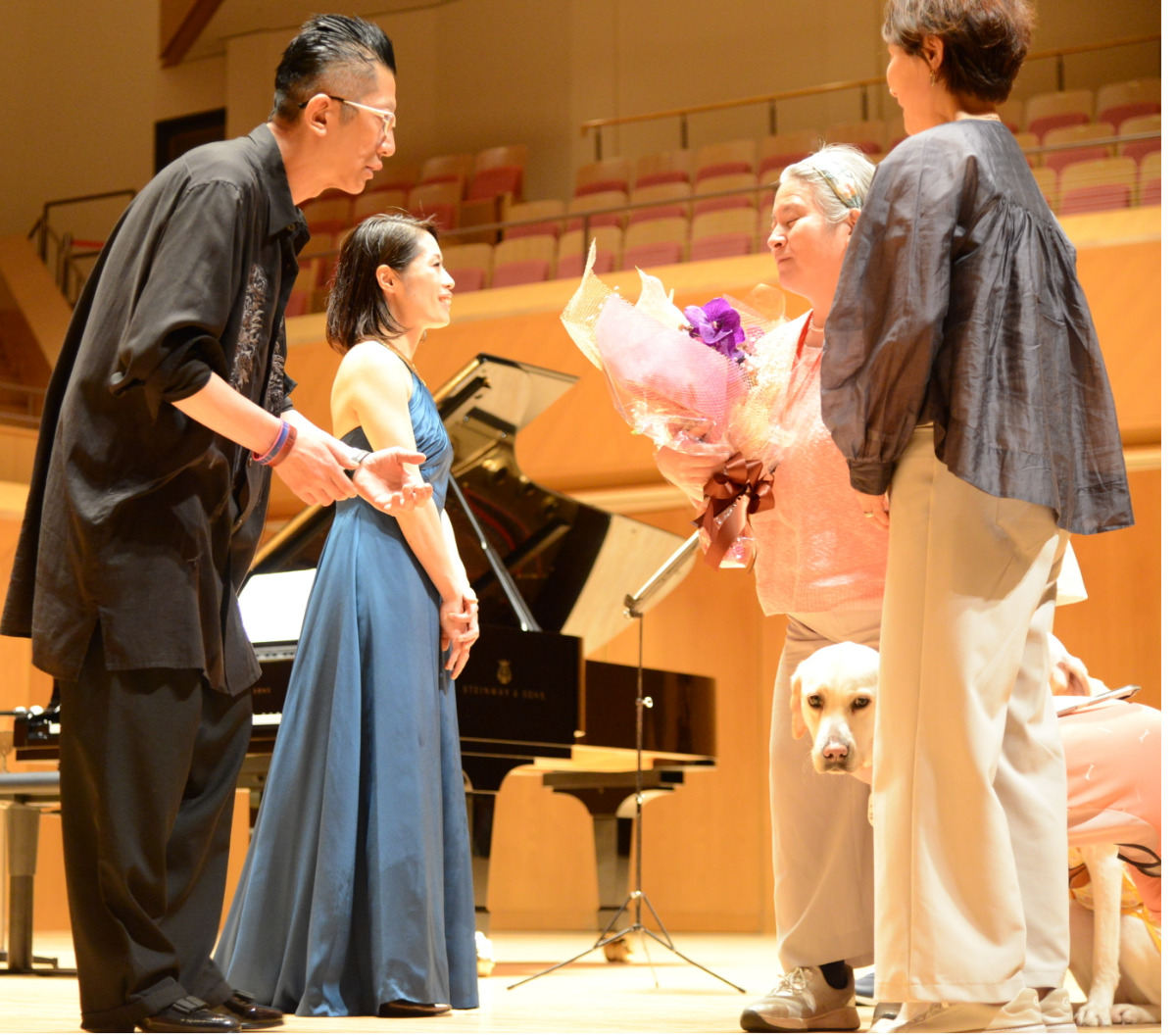 盲導犬を傍らに観客から出演者に花束が手渡された(写真左手前が石田さん、奥が上原さん)