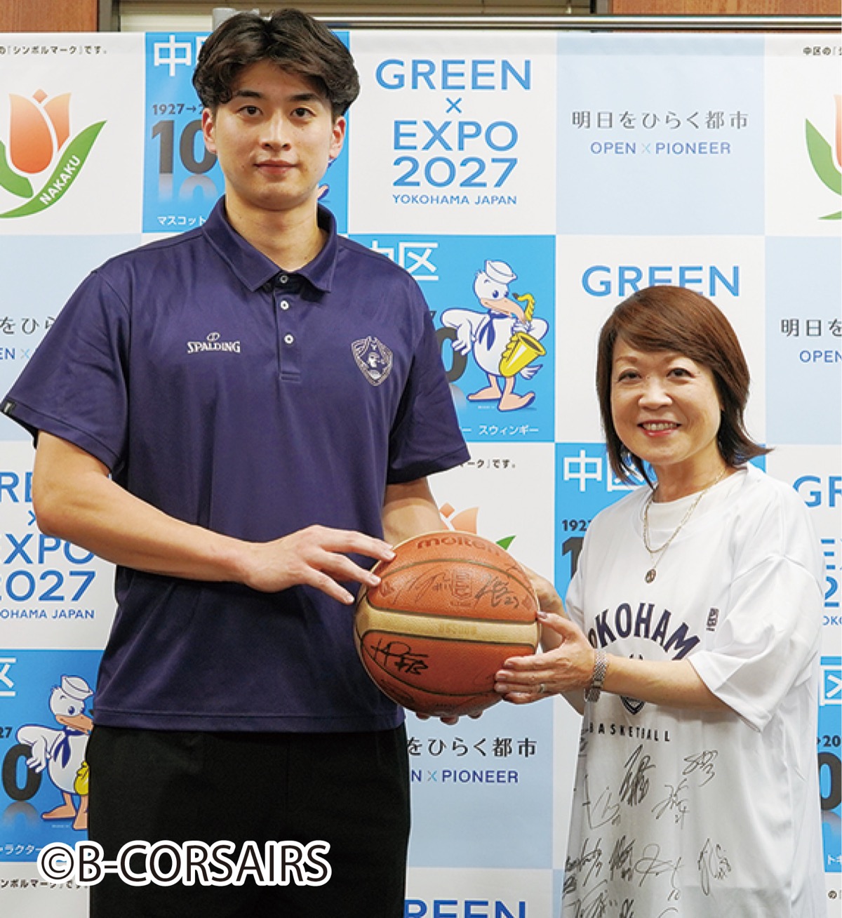 全選手のサイン入りボールとTシャツを受け取った永井区長(右)。新井選手と記念撮影