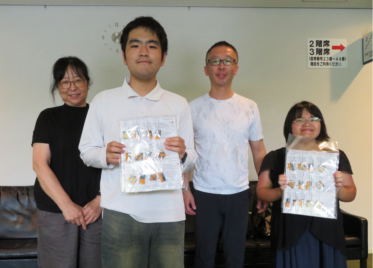 ウクライナ国立バレエ団芸術監督の寺田宜弘さん(後列右)にチャームを手渡したメンバー2人と青山施設長(同左)=8月11日、提供写真