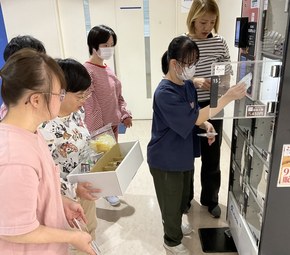 ロッカーに納品する利用者たち。はな工房には毎日約20人が通い、菓子のほか、レジンアクセサリーや機織り小物の製作販売、委託作業などを行う
