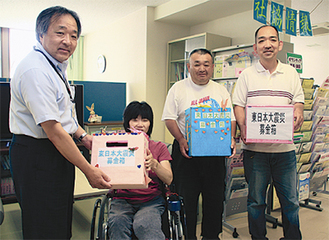 社会福祉協議会の門倉晴義事務局長（左）に義援金を手渡した