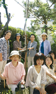 長崎さんが贈ったエノキを取り囲む和枝さん　（後列右から２人目）と豆の木文庫のスタッフら