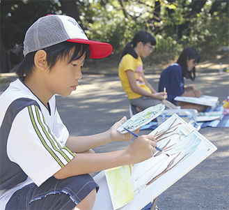 公園内の風景を描く児童