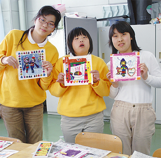 展示する作品を手にする左から泉沙耶さん、長谷川真子さんと部長の関さん