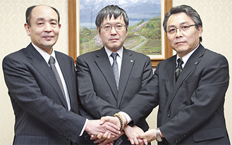 固い握手を交わす（左から）青山会長、北浜会長、川田会長