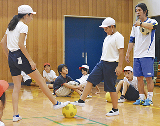 遠藤さん（右）の指導でボールを奪い合う児童