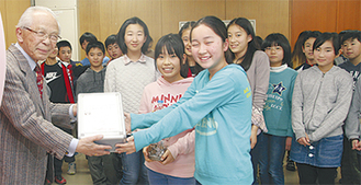 大津会長（左）に募金を渡す児童