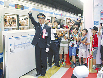 最初の快速電車の出発を合図する石坂寿邦駅長