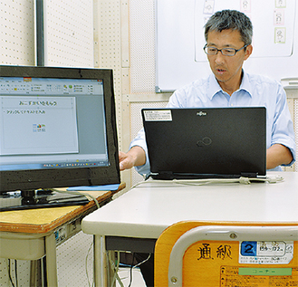 生徒と学習する教室でパソコンを操作する内山教諭