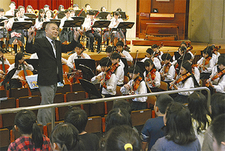 オーケストラ部の演奏に合わせて歌う児童