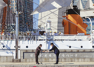帆船日本丸の前で感謝状を受け取る山本社長（右）