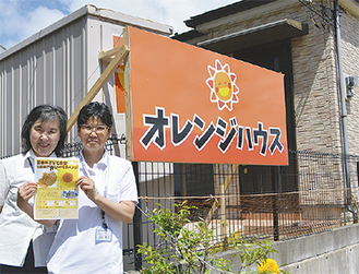 オレンジハウスの前で案内紙を持つ梅澤さん（左）と山田さん
