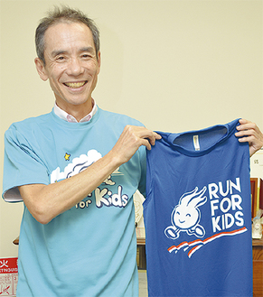 「ランまるＴシャツ」を着てランナー専用シャツを持つ山崎さん