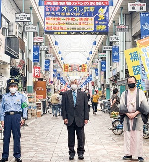 商店街に掲げられた幕（写真後方）。左から田中南警察署長、高橋理事長、桂枝太郎さん