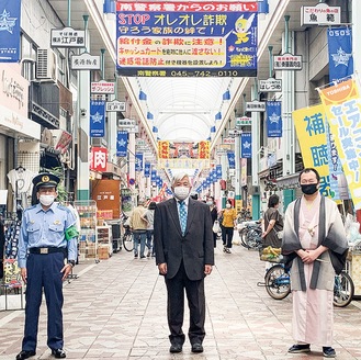 ７月に掲げられた幕（写真後方）。左から田中南警察署長、高橋理事長、桂枝太郎さん
