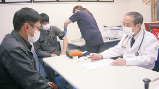 接種前の問診を受ける社員（左）