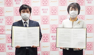 協定書を手にするジェイコムの上田康夫局長（左）と松山弘子区長