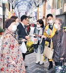 買い物客に啓発物を配る長谷川支部長（中央左）