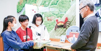 小網代インフォメーションブースで岸さん（右）に寄付金の目録を渡す太田小６年生