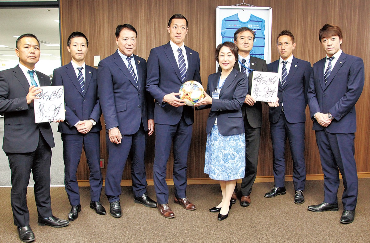 松山区長(中央右)にサインボールを手渡す南選手(同左)と関係者