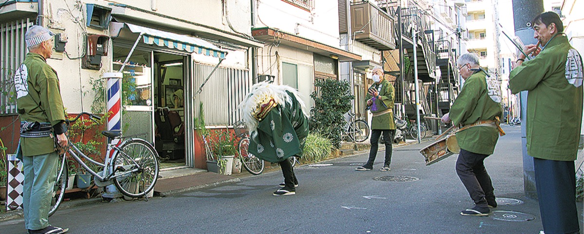 理髪店の前で舞う「真金囃子」の獅子舞