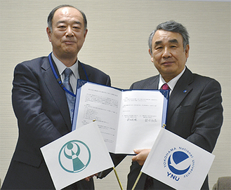 協定書を手に笑顔を見せる鈴木区長（左）と鈴木学長（右）