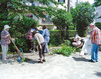 団地の敷地内を清掃する自治会メンバー