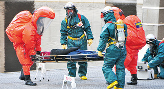 化学防護服を着用し負傷者を救出する消防隊員