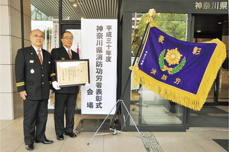 表彰旗を前に笑顔の杉山団長（写真左）と久保田副団長
