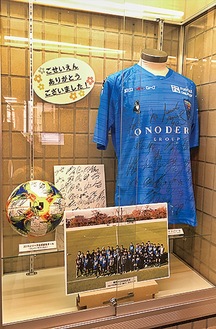 サインが記されたユニフォームやボールなどが展示されている