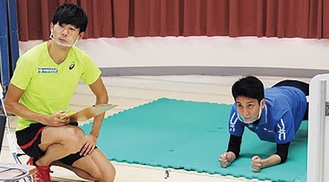 カメラに向かいトレーニングを指導する長谷川選手（左）