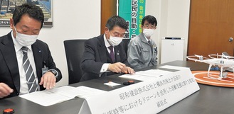 協定書に調印する出口区長（写真左）と昭和建設の工藤社長（同中央）